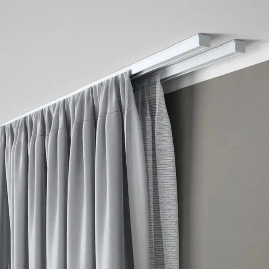 Double rail à rideaux fixé au plafond permettant l’installation d’un voilage et d’un rideau occultant dans un intérieur contemporain.