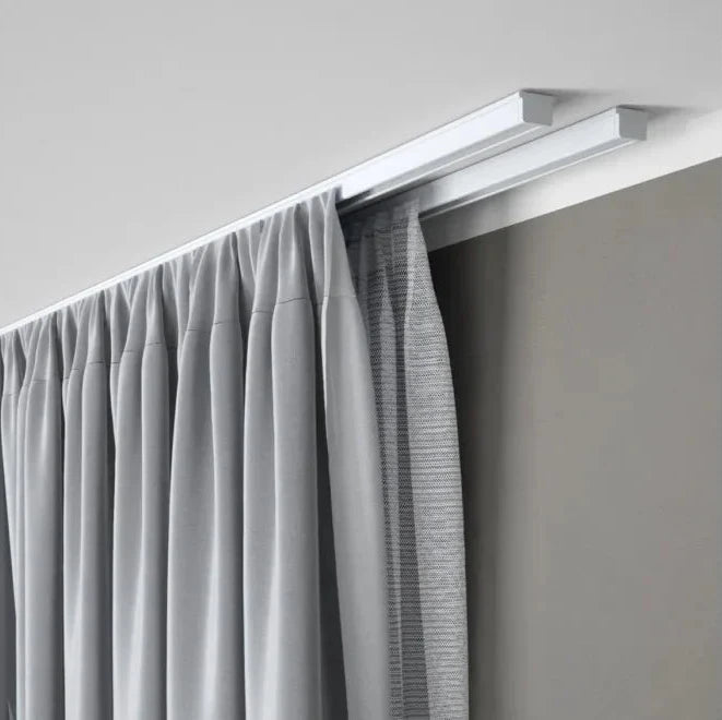 Double rail à rideaux fixé au plafond permettant l’installation d’un voilage et d’un rideau occultant dans un intérieur contemporain.