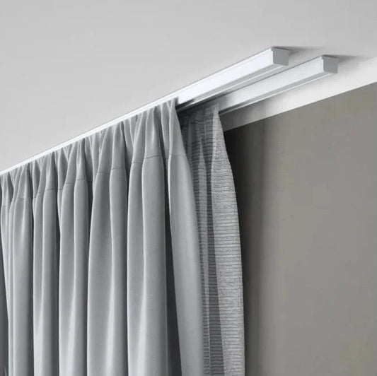 Double rail à rideaux fixé au plafond permettant l’installation d’un voilage et d’un rideau occultant dans un intérieur contemporain.