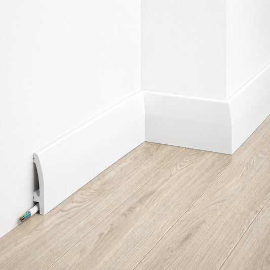 Plinthe décorative blanche MD030 installée le long d’un mur gris avec parquet bois clair, intégrant un canal pour câbles.