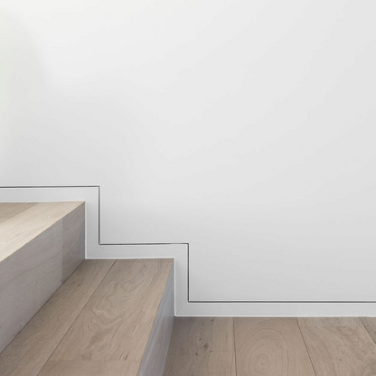 Plinthe invisible affleurante installée sur mur d’escalier, finition minimaliste avec profilé S1060.