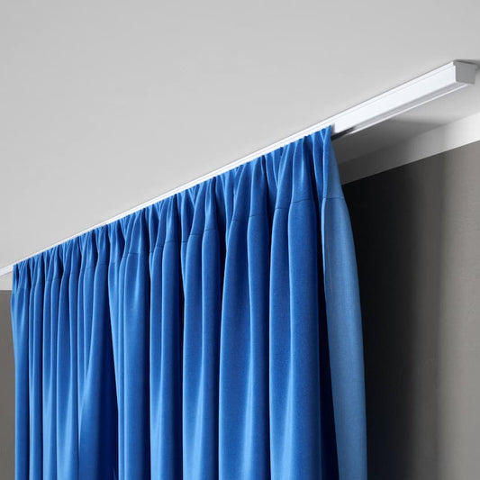 Rail à rideaux discret fixé au plafond avec rideau bleu occultant dans un intérieur moderne et minimaliste.