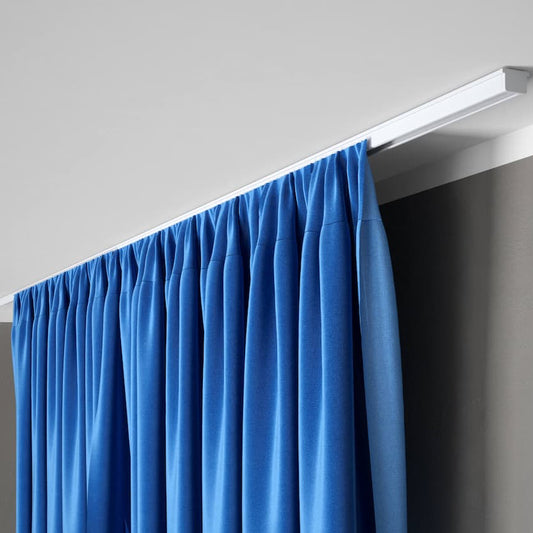 Rail à rideaux discret fixé au plafond avec rideau bleu occultant dans un intérieur moderne et minimaliste.