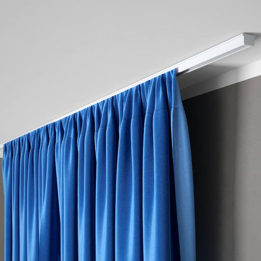 Rail à rideaux discret fixé au plafond avec rideau bleu occultant dans un intérieur moderne et minimaliste.