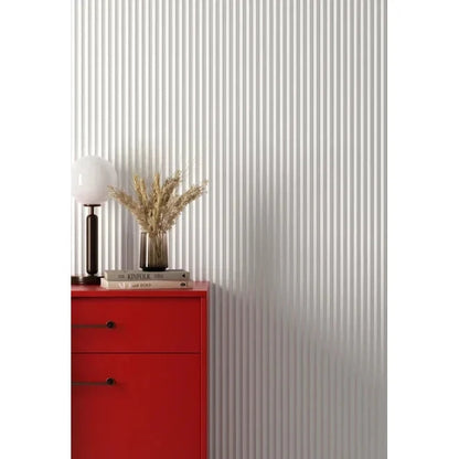 Panneaux Vivid blancs au relief triangulaire derrière un meuble rouge et une lampe