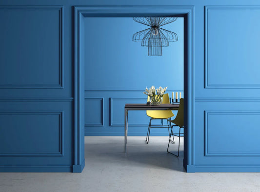 Moulure murale MD314 installée sur un mur bleu dans une salle à manger moderne, parfaite pour structurer et embellir l’espace
