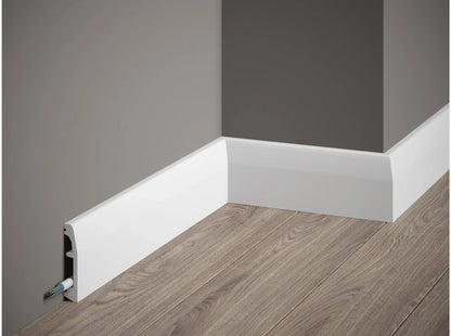 Plinthe décorative blanche MD017 200x6,9x1,4 cm avec cache-câble intégrée posée sur mur gris et sol effet bois Plinthe décorative blanche MD017 200x6,9x1,4 cm avec cache-câble intégrée posée sur mur gris et sol effet bois