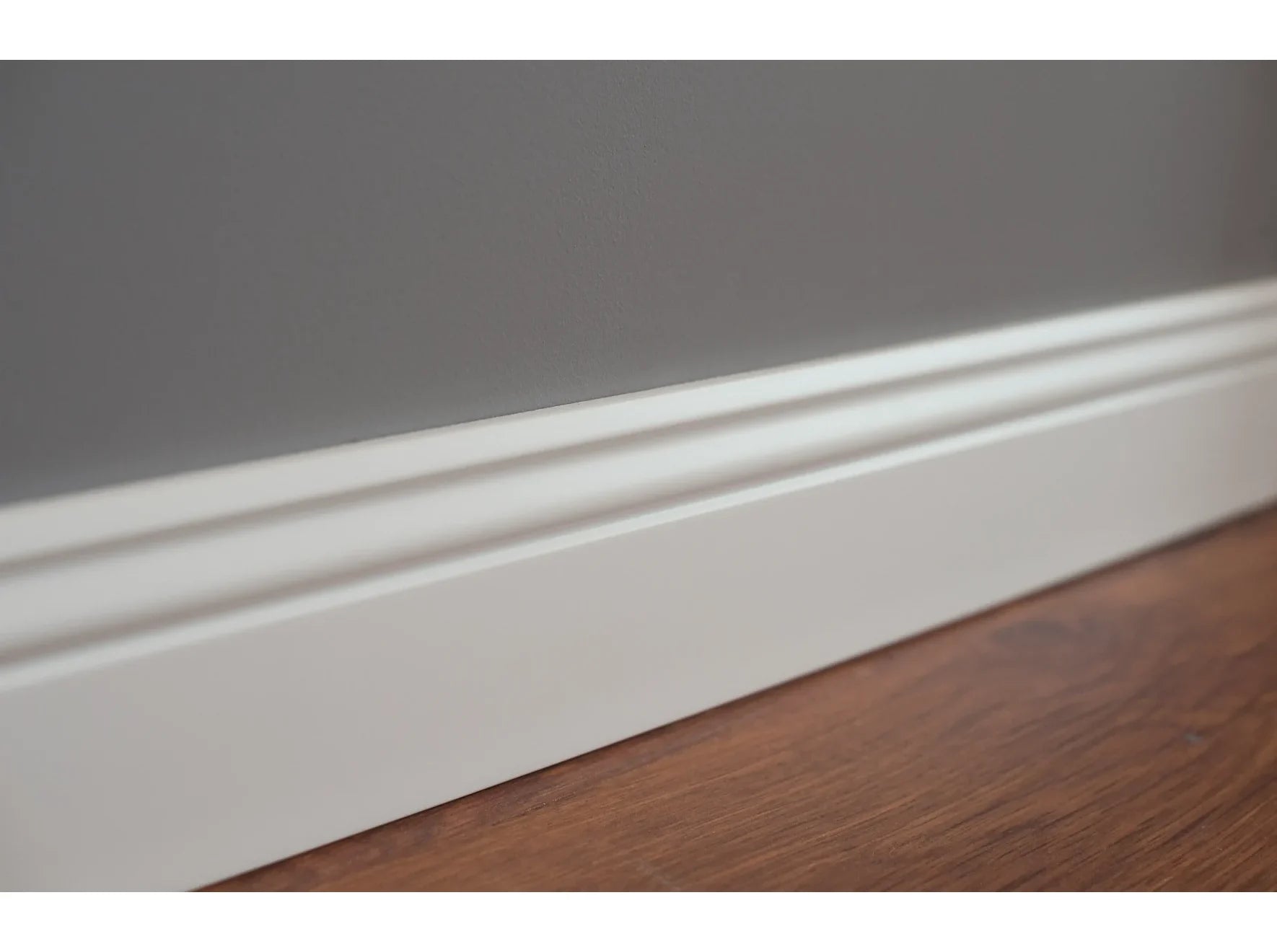 Détail de la plinthe MD094 – finition blanche et moulurée – pose contre mur gris – 200 x 9,4 x 1,2 cm