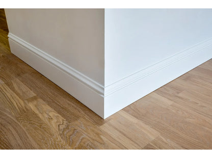 Plinthe moulurée MD358 installée sur un mur blanc et un sol en chêne clair, vue en angle – design élégant et sobre