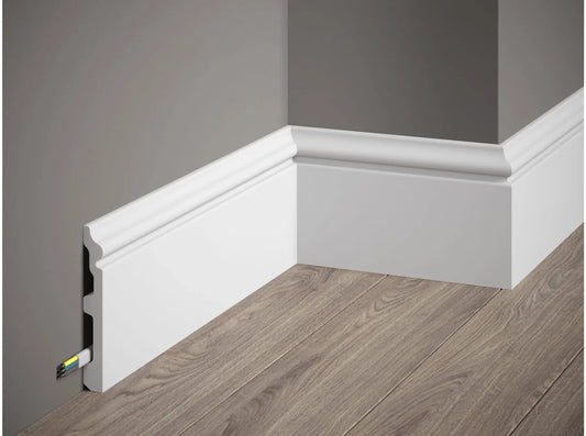 Plinthe décorative blanche MD358 avec passage de câbles intégré, installée contre un mur gris et un parquet bois clair – 200 x 11,7 x 1,4 cm