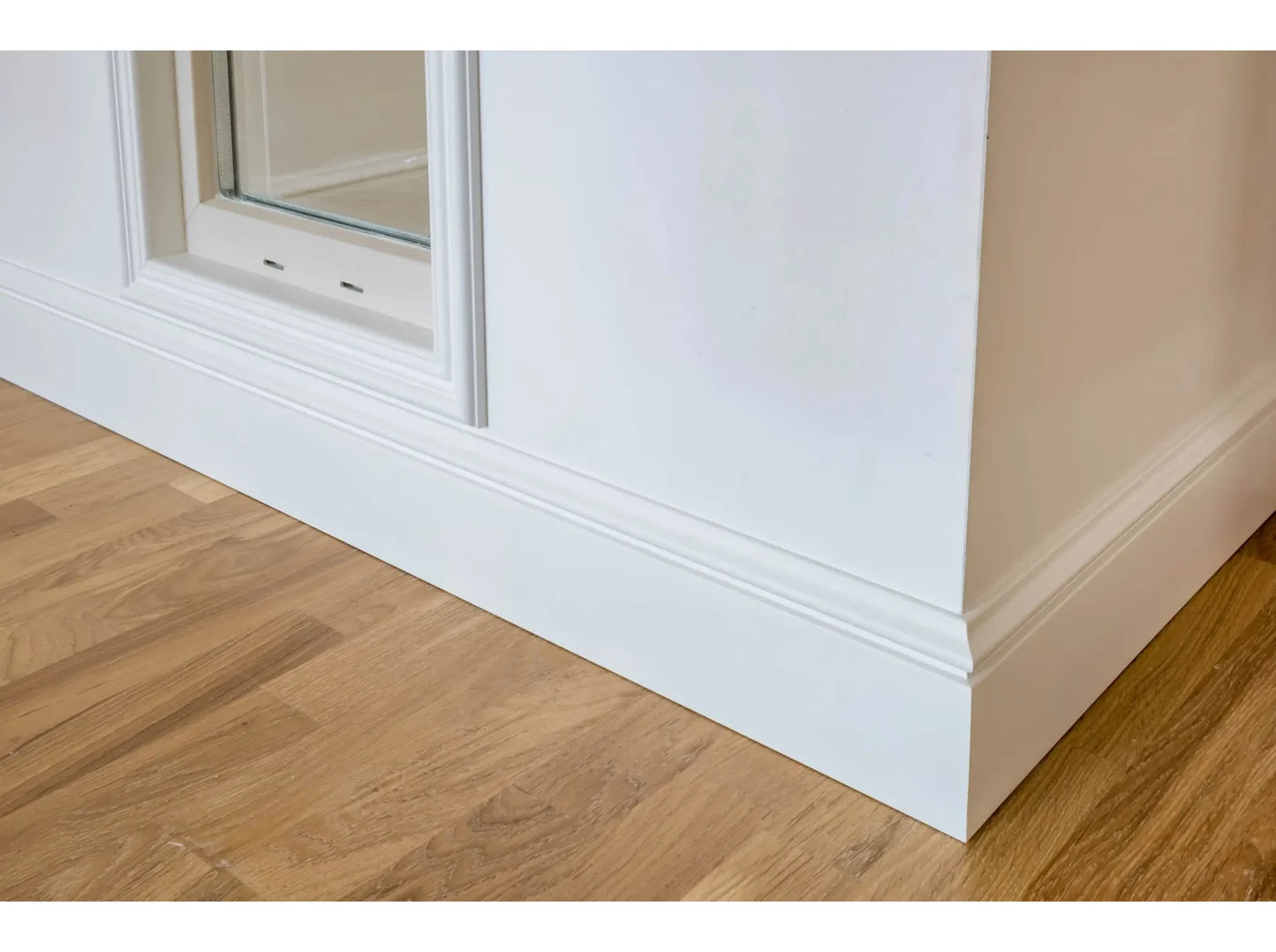 Plinthe décorative MD358 blanche posée sous une fenêtre avec parquet bois – finition soignée et classique