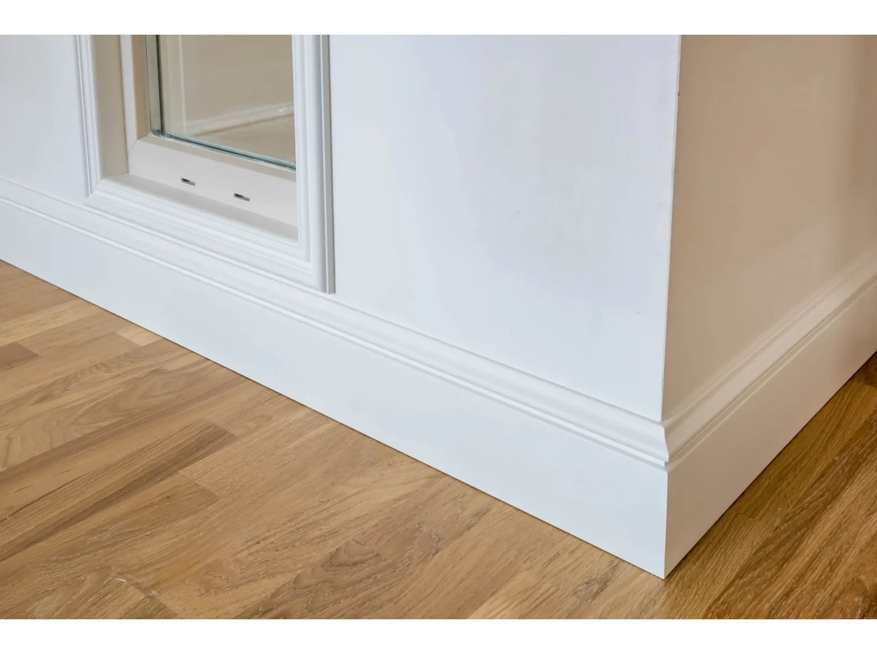 Plinthe décorative MD358 blanche posée sous une fenêtre avec parquet bois – finition soignée et classique