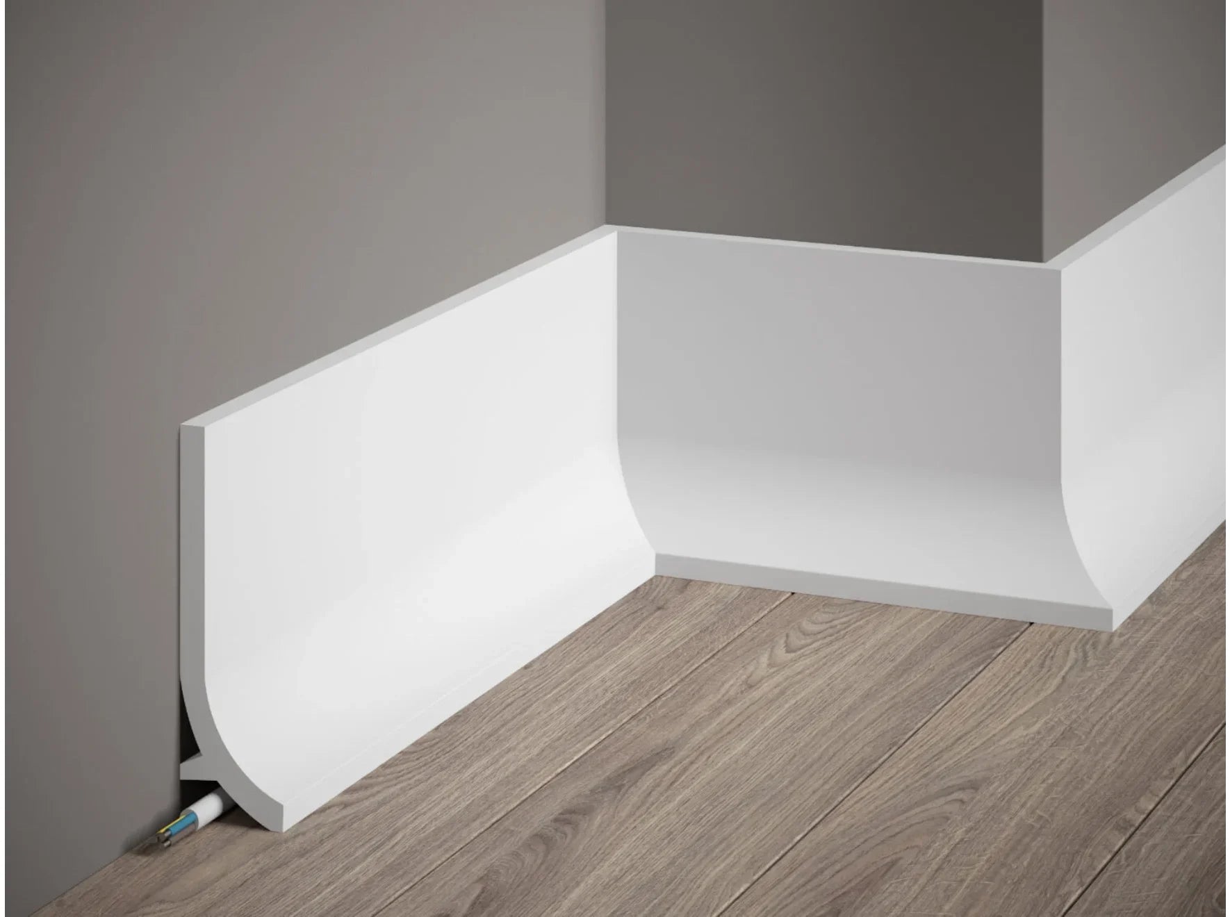 Plinthe décorative QS011 blanche à bord arrondi avec passage de câbles, installée sur mur gris et sol effet bois – dimensions 200 x 13,5 x 4 cm