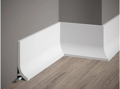 Plinthe décorative QS011 blanche à bord arrondi avec passage de câbles, installée sur mur gris et sol effet bois – dimensions 200 x 13,5 x 4 cm